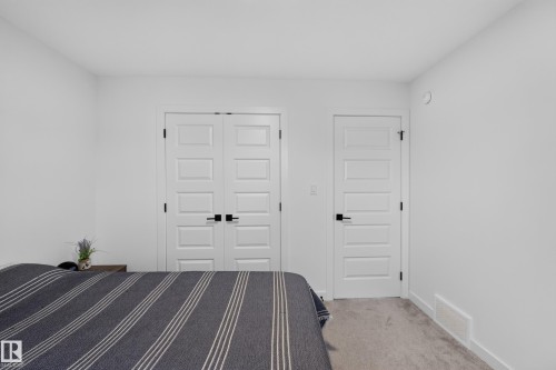 White paneled doors with matte black hardware, light neutral carpeting, white baseboards, and bright white walls - 548 Kleins Crescent, Leduc, AB 
