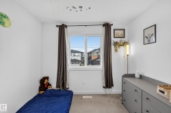 Bright room featuring a large window with dark curtain panels, light gray carpeting, white painted walls, and a built-in shelf - 