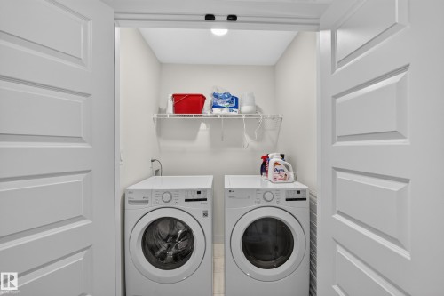 Dedicated laundry area featuring a front-loading washer and dryer set, overhead wire shelving, and bright overhead lighting - 548 Kleins Crescent, Leduc, AB 