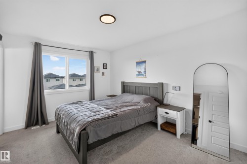 Bedroom featuring a large window, carpeted flooring, and a flush-mount ceiling light - 548 Kleins Crescent, Leduc, AB 