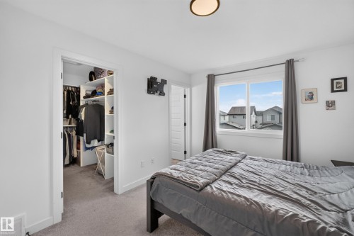 Bedroom featuring a large window, light gray carpeting, and a built-in closet organization system - 548 Kleins Crescent, Leduc, AB 