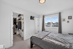 Bedroom featuring a large window, light gray carpeting, and a built-in closet organization system - 