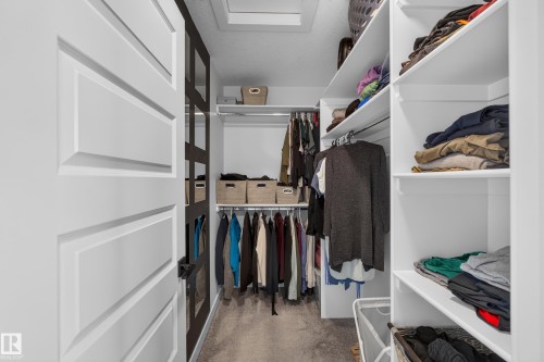 Custom closet organization system featuring white shelving, multiple hanging rods, and recessed lighting - 548 Kleins Crescent, Leduc, AB 