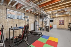 Unfinished basement featuring exposed wood joists, utility infrastructure, a window, and concrete flooring - 