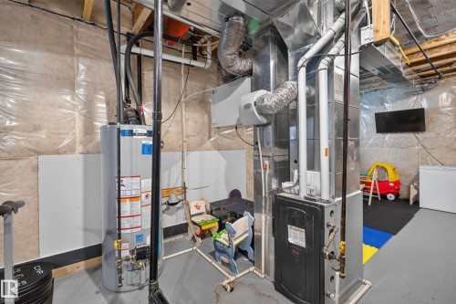 Utility area featuring a water heater, furnace, and exposed ductwork - 548 Kleins Crescent, Leduc, AB 