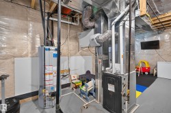 Utility area featuring a water heater, furnace, and exposed ductwork - 