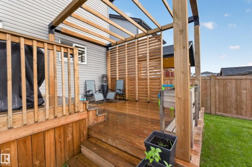 Multi-level wood deck featuring a slatted privacy screen, an open pergola, and steps descending to a grass lawn - 548 Kleins Crescent, Leduc, AB 