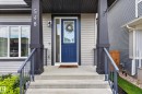 Modern facade featuring light gray siding with contrasting dark trim and a vibrant blue entry door - 548 Kleins Crescent, Leduc, AB 