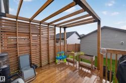 Spacious wood deck featuring an open pergola structure and horizontal slat privacy screen - 