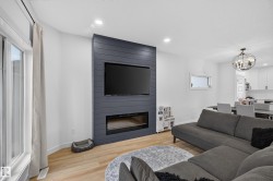 Living area featuring a floor-to-ceiling accent wall with a built-in linear fireplace and wood-finish flooring - 