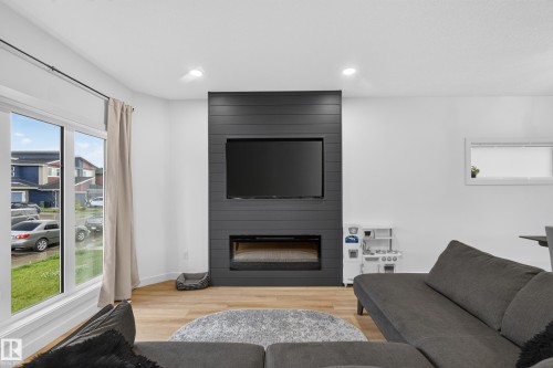 Living space featuring a prominent dark shiplap accent wall with an integrated television and electric fireplace - 548 Kleins Crescent, Leduc, AB 