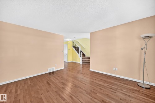 Spacious interior featuring wood-finish flooring, light-toned walls, and white baseboards - 211 59 Street, Edmonton, AB 