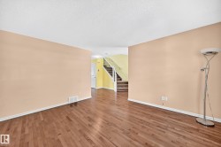 Spacious interior featuring wood-finish flooring, light-toned walls, and white baseboards - 