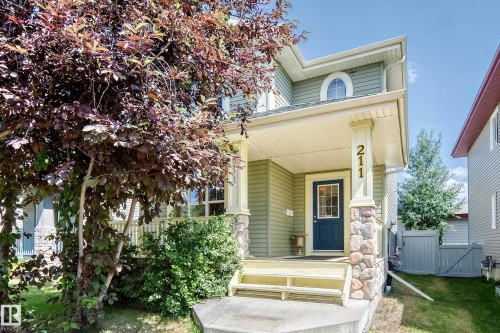 Front exterior with light green siding, a covered porch, and a dark blue entry door - 211 59 Street, Edmonton, AB 