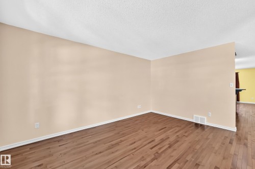 Open-concept interior featuring wood-finish flooring, light-toned walls, and white baseboards - 211 59 Street, Edmonton, AB 