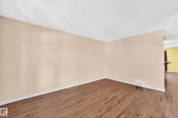 Open-concept interior featuring wood-finish flooring, light-toned walls, and white baseboards - 