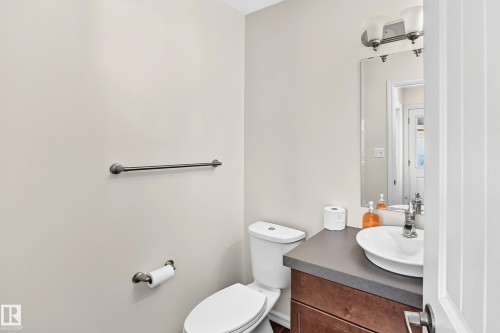 Modern bathroom featuring a wood-finish vanity, a vessel sink, a mounted mirror, and an overhead light fixture - 211 59 Street, Edmonton, AB 