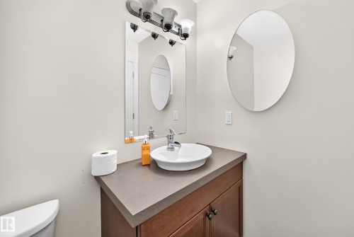 Vanity with a vessel sink, dark brown cabinetry, and a dark countertop - 211 59 Street, Edmonton, AB 