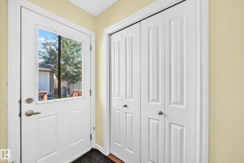 Entryway featuring a white paneled door with an upper window insert, brushed nickel hardware, and a dark floor mat - 211 59 Street, Edmonton, AB 