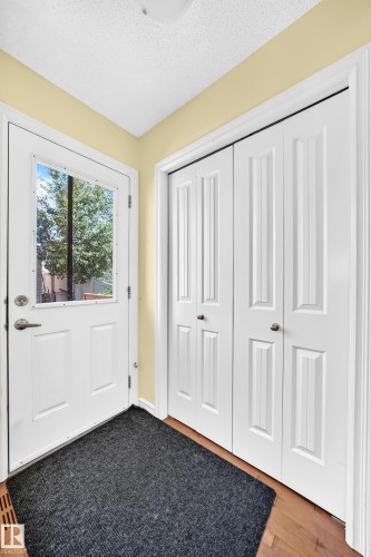 Entryway featuring a glass-paneled door, two panel doors, wood-finish flooring, and light-toned walls - 211 59 Street, Edmonton, AB 