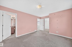 Carpeted room with a flush-mount ceiling light fixture, featuring a doorway to a bathroom with tile flooring and a vanity, and a separate doorway leading to a walk-in closet - 