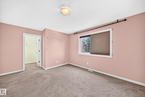 Carpeted room featuring a window with cellular shades, a ceiling-mounted light fixture, white trim, and a doorway leading to a walk-in closet - 211 59 Street, Edmonton, AB 