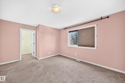 Carpeted room featuring a window with cellular shades, a ceiling-mounted light fixture, white trim, and a doorway leading to a walk-in closet - 