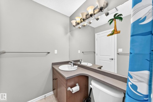 Bathroom featuring a single vanity with a dark wood-finish cabinet and integrated countertop - 211 59 Street, Edmonton, AB 