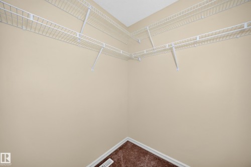 Spacious closet featuring white wire shelving, neutral wall paint, and brown carpeting - 211 59 Street, Edmonton, AB 