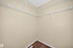 Spacious closet featuring white wire shelving, neutral wall paint, and brown carpeting - 