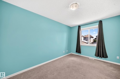 Room featuring a window with white trim, light blue walls, and a textured ceiling - 211 59 Street, Edmonton, AB 