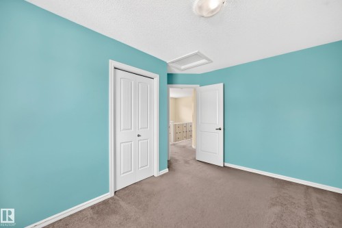 Room with light blue walls, a textured ceiling, and neutral-toned carpeting - 211 59 Street, Edmonton, AB 