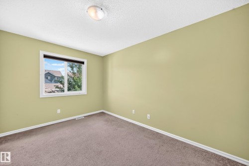Neutral wall paint, carpet flooring, a window with exterior views, white trim, and a ceiling-mounted light fixture - 211 59 Street, Edmonton, AB 
