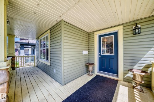 Covered front porch featuring pale green siding, a paneled door with a multi-pane glass insert, and a matching window with light trim - 211 59 Street, Edmonton, AB 