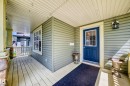 Covered front porch featuring pale green siding, a paneled door with a multi-pane glass insert, and a matching window with light trim - 211 59 Street, Edmonton, AB 