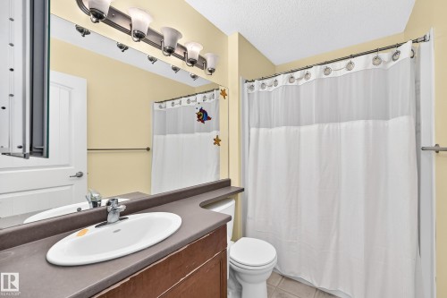 Bathroom featuring a vanity with a drop-in sink, a wall-mounted mirror, and a shower with a curtain rod - 211 59 Street, Edmonton, AB 