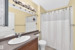 Bathroom featuring a vanity with a drop-in sink, a wall-mounted mirror, and a shower with a curtain rod - 