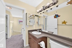 Full bathroom featuring a single vanity with an integrated sink and brown cabinetry, framed by a multi-bulb vanity light fixture - 
