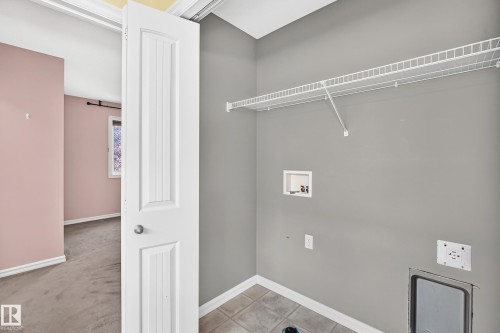 Utility space featuring light gray walls, tile flooring, and a wire shelving unit - 211 59 Street, Edmonton, AB 