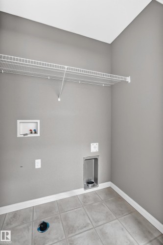 Utility room featuring light gray wall paint, white trim, tiled flooring, and a wire shelving unit - 211 59 Street, Edmonton, AB 