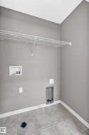 Utility room featuring light gray wall paint, white trim, tiled flooring, and a wire shelving unit - 