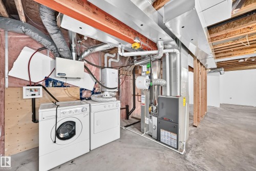 Utility area featuring a washer and dryer, furnace, water heater, and exposed ceiling joists - 211 59 Street, Edmonton, AB 