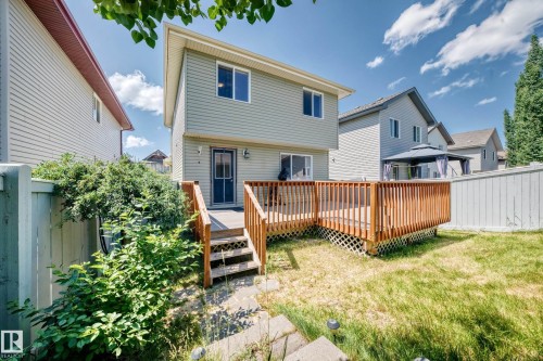 Rear exterior featuring a two-story design with siding, a wooden deck, and a sliding glass door - 211 59 Street, Edmonton, AB 