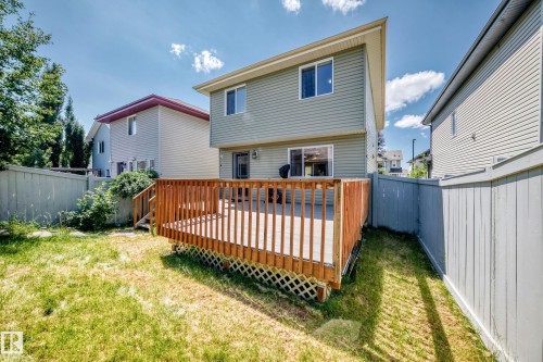 Rear exterior featuring a spacious wooden deck with railings, privacy fencing, and a grassy lawn - 211 59 Street, Edmonton, AB 
