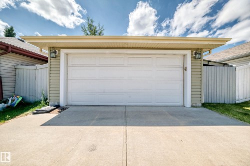 Attached garage featuring a white panel door, light green siding, and exterior wall sconces - 211 59 Street, Edmonton, AB 