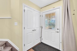 Entryway featuring a white paneled door with textured glass insert, adjacent double closet doors, and wood-finish flooring - 