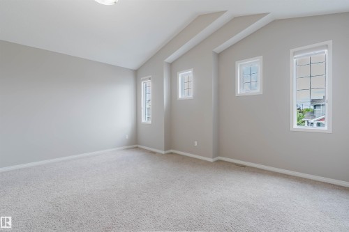 Spacious room featuring vaulted ceilings, light gray wall paint, and plush carpeting - 16627 18 Avenue, Edmonton, AB 