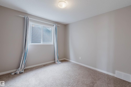 Neutral-toned wall paint with white trim, wall-to-wall carpeting, and a ceiling-mounted light fixture - 16627 18 Avenue, Edmonton, AB 