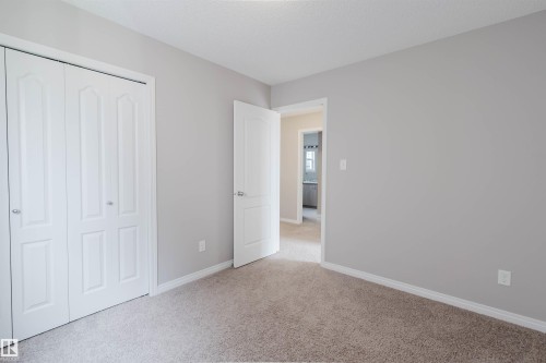 Neutral-toned room featuring light gray walls, white trim, and light brown carpeting - 16627 18 Avenue, Edmonton, AB 