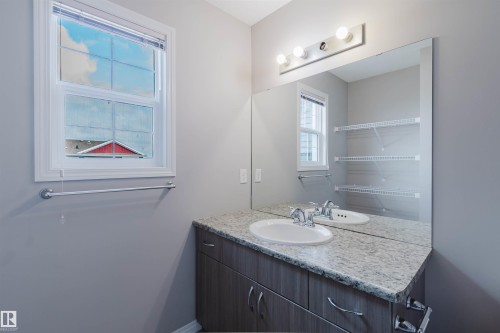 Bathroom featuring a vanity with a light-toned countertop, an under-mount sink, and a chrome faucet - 16627 18 Avenue, Edmonton, AB 